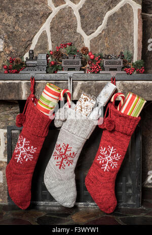 Gefüllte Strümpfe hängen an einem Kamin am Weihnachtsmorgen Stockfoto