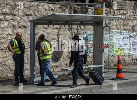 (151013)--JERUSALEM, 13. Oktober 2015 (Xinhua)--ein Ultra-orthodoxer jüdischen Mann geht vorbei an der Website eine Bus-Station-Anschlag in Jerusalem, am 13. Oktober 2015. Mindestens drei Israelis wurden getötet und 26 Verletzte in vier palästinensischen Anschlägen in Jerusalem und die Stadt der Ra'anana am Dienstag Morgen, sagte die israelische Polizei. Ein Palästinenser auf einen van mit dem Logo der Israels Nationale Telekommunikations-Unternehmen, Bezeq, überfuhr Pendler an Bushaltestellen im Geula Viertel im Zentrum von Jerusalem. Dann ging er aus seinem Wagen, stechende Passanten mit einem Messer. Rettungsdienste sagte er getötet und verletzt Stockfoto