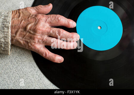 Senile Hand ist auf Vinyl-LP. Nahaufnahme der Greis oder alte Hand. Platz für Ihren Text. Stockfoto