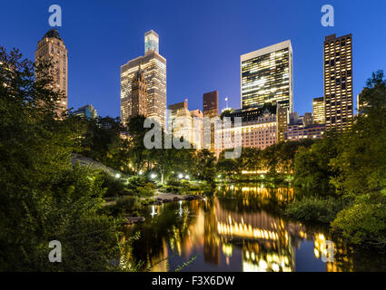 Manhattan Wolkenkratzer im frühen Abendlicht beleuchtet. Die Gebäude reflektieren im Stadtpark-Teich. New York City. Stockfoto