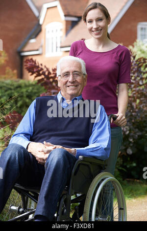 Erwachsene Tochter Vater im Rollstuhl schieben