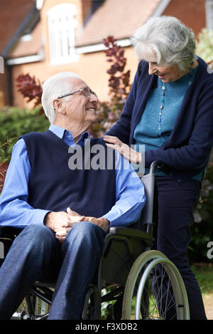 Ältere Mann im Rollstuhl geschoben von Frau Stockfoto