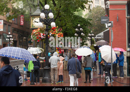 Menschen halten Sonnenschirme Gastown Dampfuhr, bewundern Vancouver. Stockfoto