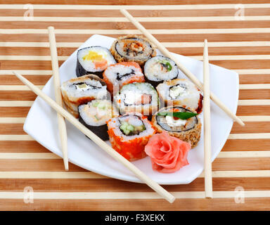 Sushi-Rollen auf dem Teller mit Stäbchen Stockfoto