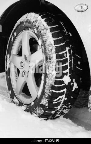 Nahaufnahme von einem Pkw-Reifen auf einer verschneiten Straße Stockfoto