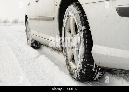 Nahaufnahme von einem Pkw-Reifen auf einer verschneiten Straße Stockfoto