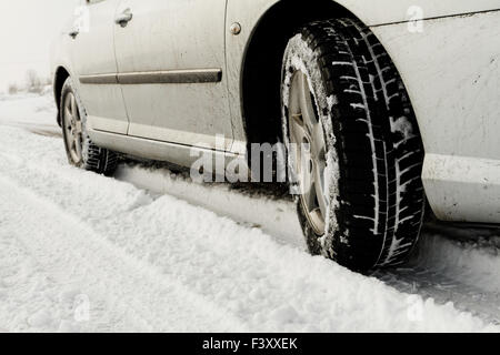 Nahaufnahme von einem Pkw-Reifen auf einer verschneiten Straße Stockfoto