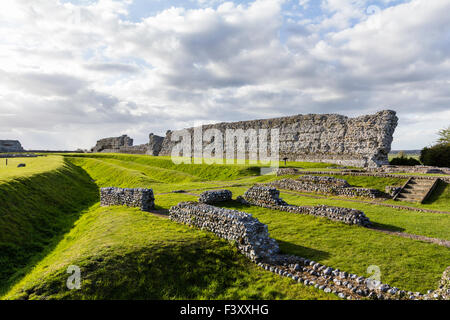 England, Richborough. Rutupiae. Römische Saxon Shore fort. 3. Jahrhundert Nordwand. Vordergrund, der Stein Stiftung Ruinen der Mansio. Blauer Himmel. Stockfoto