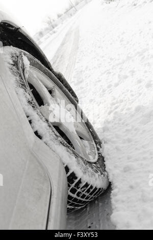 Nahaufnahme von einem Pkw-Reifen auf einer verschneiten Straße Stockfoto