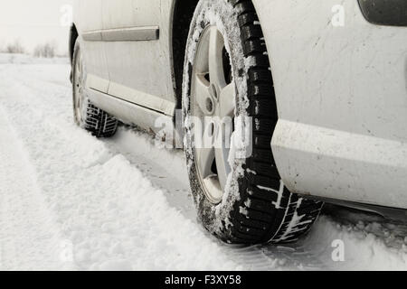 Nahaufnahme von einem Pkw-Reifen auf einer verschneiten Straße Stockfoto