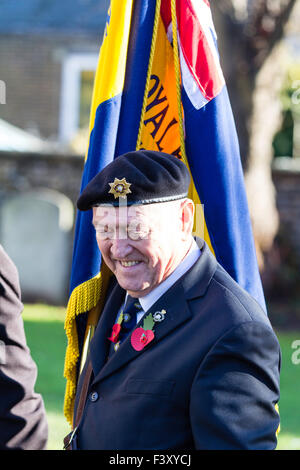 Erinnerung Sonntag. Ältere Menschen, Kriegsveteranen in Uniform, stehend mit Fahne, das Tragen eines Poppy und Lachen beim Chatten jemand Weg zur Kamera Stockfoto