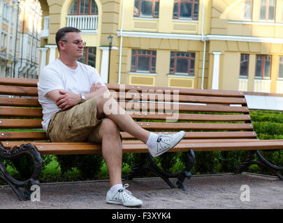 Mann sitzt auf einem städtischen Bank warten Stockfoto