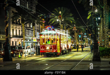 Der Kanal Straßenbahn bei Nacht unter den Neonröhren und Palm Tree Beleuchtung sorgt für ein festliches Ambiente in New Orleans, LA Stockfoto