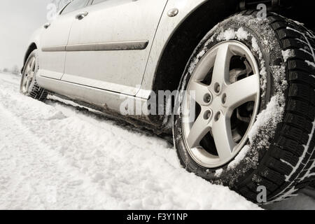 Nahaufnahme von einem Pkw-Reifen auf einer verschneiten Straße Stockfoto