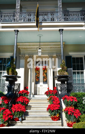 Roten Weihnachtssterne säumen die Treppe als Weihnachtsschmuck zu Veranda & Eingang zum Herrenhaus im Garden District, New Orleans, LA Stockfoto