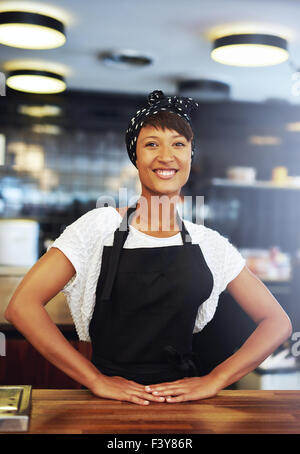 Sicher erfolgreiche junge Kleinunternehmer stehen hinter der Theke in ihrem Café geben der Kamera eine glückliche welcomi Stockfoto