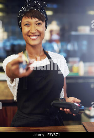 Enthusiastisch ziemlich Afrikanische amerikanische Inhaber eines kleinen Unternehmens mit einem schönen lebhaften Lächeln zurück Übergabe einer Kreditkarte nach Prozess Stockfoto