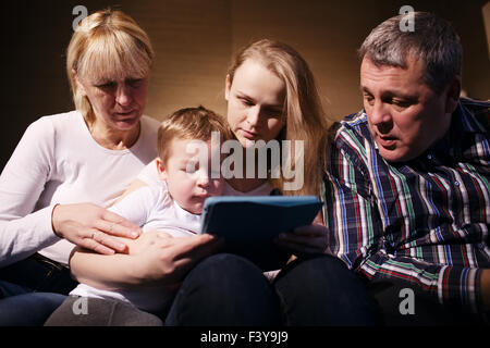 Familie beobachten junge Rollenspiel auf touchpad Stockfoto