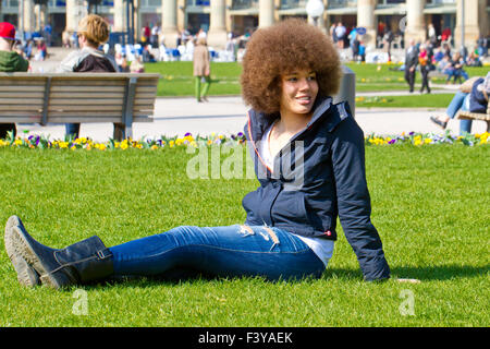 Junge Afro Frau sitzt in einem park Stockfoto