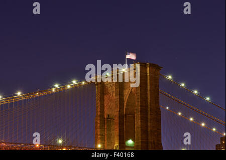 Nahaufnahme einer Säule von der Brooklynbridge mit Fahne in der Nacht Stockfoto