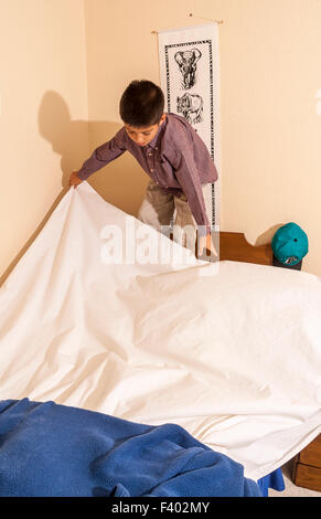 Young Korean/American Boy 8-10 Jahre Olds Jahre alt sein Bett machen.   Herr © Myrleen Pearson Stockfoto
