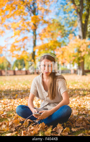 Frau sitzt auf dem Boden hören Musik Ipod Stockfoto