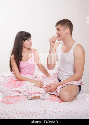 Eine Mädchen Schokolade geben Kerl im Bett nicht Stockfoto