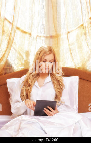 Junge glücklich blonde Frau im Bett Stockfoto