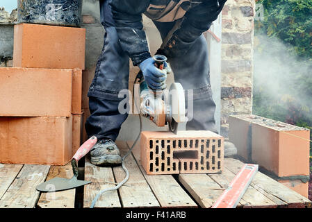 Bauarbeiter mit Mauerwerk sah Betonblöcke um eine neue Mauer errichten schneiden Stockfoto