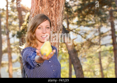 Mädchen hält eine Birne im Park mit Sonnenuntergang im Hintergrund und Objektiv flare-Effekt Stockfoto