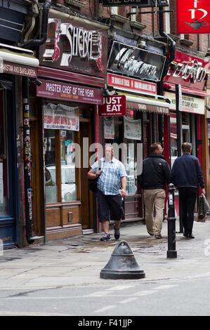 Fußgänger, vorbei an ein paar Curry-Restaurants auf der Brick Lane im Osten Londons Stockfoto