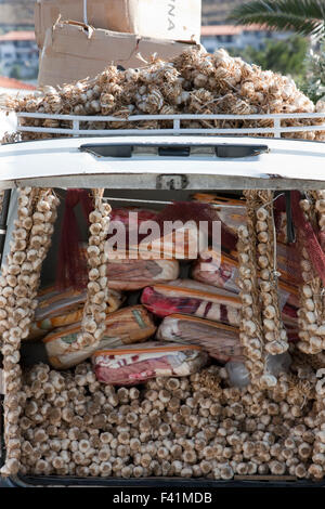 Haufenweise getrocknete Knoblauchzehen zum Verkauf unter Packungen mit Decken auf eine Zigeunerin Hausierer van hängen. Stockfoto