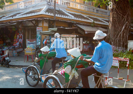 zwei männliche Cyclo-Fahrer Überführung Touristen durch die Altstadt Hoi An, an der vietnamesischen Küste, Vietnam Stockfoto