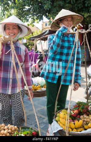 zwei vietnamesische Damen in Hoi An, verkaufen Obst aus ihrer Joche auf ihre Schultern, Zentral-Vietnam durchgeführt Stockfoto