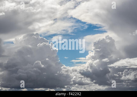 Wogende Gewitterwolken mit Feuchtigkeit reichen dunklen Böden umgeben ein Stückchen blauen Himmel im zeitigen Frühjahr. Stockfoto