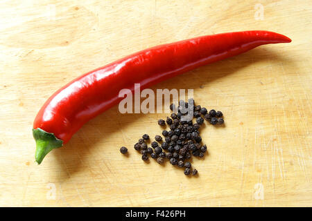 lange rote Paprika glänzende Küche Board mit getrockneten schwarzen Pfeffer Stockfoto