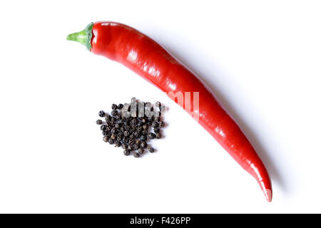 lange rote Paprika glänzend auf weißem Hintergrund mit getrockneten schwarzen Pfeffer Stockfoto