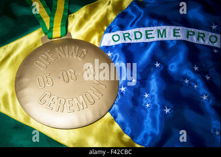 Zeremonielle gold Medaille zur Erinnerung an die Eröffnungsfeier auf 08.05.16 auf einem glänzenden brasilianische Flagge Hintergrund Stockfoto