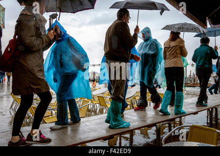 Markusplatz, Venedig, Italien. 14. Oktober 2015. Menschen Sie auf der Piazza San Marco tragen Regenponchos und Galoschen während der Acqua Alta oder "Hochwasser" die außergewöhnliche Flut-Gipfel, die in regelmäßigen Abständen, in der nördlichen Adria auftreten. Foto von: Richard Wayman Stockfoto