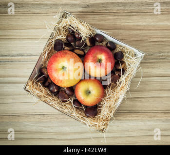 Drei Äpfel und Kastanien in der Box auf den hölzernen Hintergrund. Stockfoto