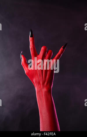 Beängstigend teuflische Hand zeigt Heavy-Metal-Geste, Studio gedreht auf rauchigen Hintergrund Stockfoto