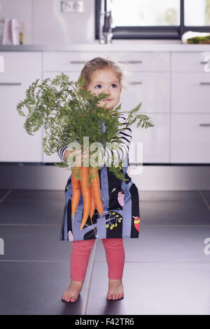 Kleine Mädchen halten frische Karotten Stockfoto