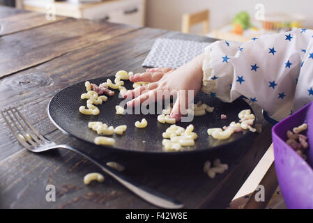 Kind essen Makkaroni mit der Hand abgeschnitten Stockfoto