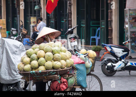 Reife Dame vietnamesische Frau verkaufen Melonen Früchte aus ihrem Fahrrad in Hanoi old Quarter Hauptstadt, Vietnam Stockfoto