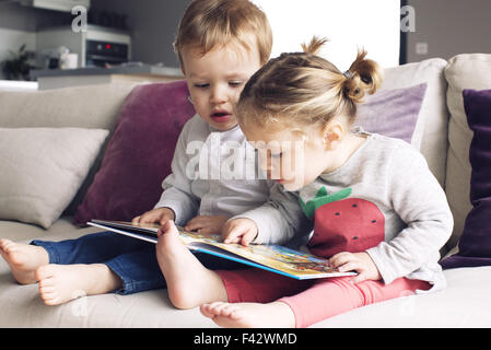 Junge Geschwister miteinander im Buch suchen Stockfoto