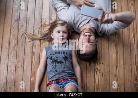 Kleine Mädchen und Vater auf Boden zusammen Smartphone betrachten Stockfoto