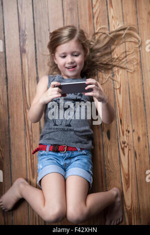 Kleines Mädchen auf Boden mit smartphone Stockfoto