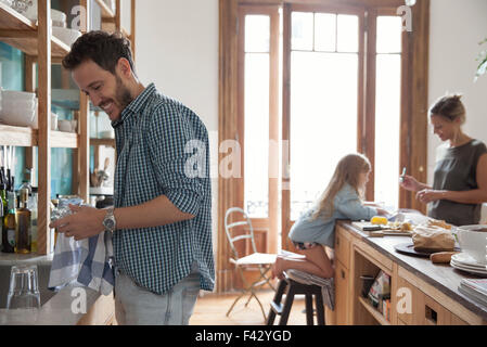 Familie in Küche, Mann trocknen Speisen im Vordergrund Stockfoto