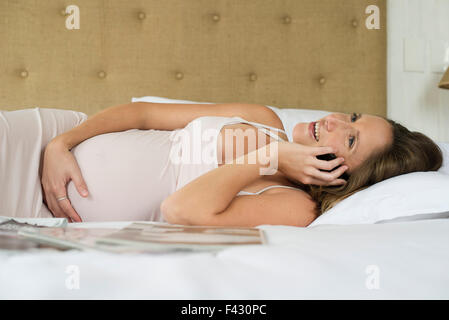 Schwangere Frau mit Handy, mit Freunden und Familie in Kontakt zu bleiben Stockfoto