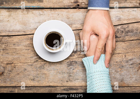 Mann hält in der Nähe von einer Tasse Kaffee Draufsicht Bild auf hölzernen Hintergrund Frauenhand. Freundschaft Kaffee Hintergrund Stockfoto